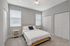 Inviting bedroom with soft gray walls, elegant plush carpet, and dual windows providing natural light. Features a cozy bed with a stylish headboard and matching bedside tables for a serene retreat.