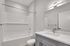Bright and modern bathroom featuring a sleek vanity, elegant white tile, and a spacious bathtub.