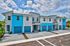 Modern townhouse row with vibrant blue accents and spacious driveways under a clear sky.