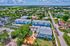 Vibrant aerial view showcasing modern blue and white apartment complex, surrounded by lush greenery and convenient access to nearby amenities.