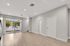 Contemporary open living space with elegant wood flooring, large glass doors, and abundant natural light.