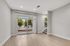 Modern living space with sleek hardwood flooring, large sliding glass doors opening to a private outdoor area, and a cozy carpeted staircase with natural light.