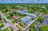 Vibrant aerial view of a modern apartment complex surrounded by lush greenery, showcasing convenient parking and unique blue accents in a thriving residential area.