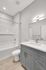 Modern bathroom design with elegant gray cabinetry, sleek marble countertop, and pristine white bathtub.