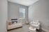 Charming nursery with cozy crib, plush seating area, and soft carpet accented by natural light for a serene ambiance.