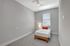 Bright and cozy bedroom with a modern ceiling fan, featuring a single bed dressed in crisp white linens and a plush orange accent pillow, inviting relaxation.