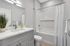 Elegant bathroom interior showcasing a modern vanity with a sleek faucet and a pristine bathtub with shower curtains.