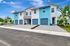 Modern townhouse exterior with a fresh blue and white facade, two-car garages, and lush landscaping under a vibrant blue sky.