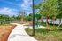 Charming community park with lush greenery, a winding path, and a vibrant picnic area under a bright blue sky.
