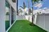 Charming outdoor space featuring lush artificial grass, elegant glass doors, and tall palm trees, perfect for relaxation and entertaining.