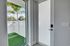 Bright entryway with modern glass door and lush artificial grass, offering a seamless blend of indoor-outdoor living.