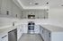 Modern kitchen with sleek gray cabinetry, stainless steel appliances, and elegant white countertops.