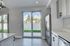 Modern kitchen with stainless steel appliances, white cabinetry, and large glass doors opening to a lush green backyard, offering a bright and inviting space.