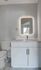Modern bathroom with sleek white vanity, elegant marble flooring, and a stylish LED-lit mirror.