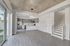 Modern open-concept living area with sleek kitchen, featuring stainless steel appliances, stylish pendant lighting, and textured ceiling, adjacent to a bright space with large sliding glass doors and a contemporary staircase.