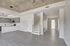 Modern open-concept loft featuring sleek kitchen cabinetry, stylish pendant lights, and elegant grey hardwood floors.