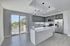 Contemporary kitchen with sleek grey cabinetry, stainless steel appliances, and a large island, complemented by modern pendant lighting and ample natural light through sliding glass doors.