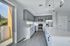 Sleek modern kitchen with stainless steel appliances, ample cabinet space, and elegant pendant lighting; natural light pours in through large glass doors.