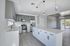 Modern kitchen with sleek grey and white cabinetry, stainless steel appliances, and elegant pendant lighting opening to a spacious, light-filled living area.