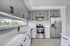 Modern kitchen with sleek stainless steel appliances, elegant gray cabinetry, and large window offering natural light.