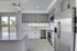 Modern kitchen with sleek stainless steel appliances, elegant gray cabinets, and expansive windows showcasing lush green views.