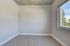 Bright and airy room with modern gray flooring and a large window offering a scenic view, ideal for a cozy living space.