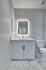 Contemporary bathroom featuring sleek white cabinetry, elegant marble flooring, and a modern backlit mirror.