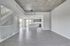 Sophisticated open-concept apartment with modern kitchen, high ceilings, gray wooden floors, and elegant fixtures.
