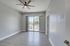 Bright, modern room featuring sleek wood flooring, a stylish ceiling fan, and large sliding doors leading to a balcony with a scenic view.