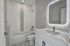 Modern bathroom featuring elegant textured wall tiles, illuminated mirror, and sleek fixtures for a luxurious feel.