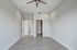 Bright, spacious room with modern gray flooring, a sleek ceiling fan, and closet space, perfect for a stylish living area.