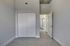 Modern bedroom with sleek grey walls, ample closet space, and a bright hallway leading to other rooms.