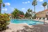 Inviting outdoor pool area with sun loungers, surrounded by lush palm trees, offering a tropical retreat for relaxation and enjoyment.