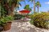 Charming outdoor patio area with lush greenery, a red umbrella, and seating for a relaxing tropical escape.