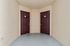 Charming apartment entrance featuring two inviting doorways with stylish maroon doors and cozy stucco walls.