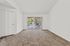 Bright living room with plush carpet and large sliding glass doors opening to a balcony with serene views.