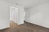 Bright and spacious room with fresh carpeting, pristine white walls, and a peek into a modern bathroom with wood-style flooring.