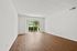 Bright and spacious living room with elegant hardwood flooring and large sliding glass doors opening to a lush outdoor view.