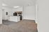 Modern open-concept apartment featuring a sleek kitchen with wooden cabinets, integrated appliances, and a spacious living area with plush carpeting.