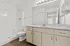 Modern bathroom with elegant marble countertop, ample storage, and bright vanity lighting, showcasing a sleek shower and stylish wood flooring.