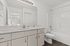 Modern bathroom with sleek white finishes, a spacious countertop, large mirror, and elegant lighting.