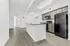 Modern kitchen with sleek black appliances, spacious island, and elegant wood flooring in a bright, airy setting.