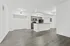 Bright, open-concept kitchen and living area featuring sleek wood flooring, modern cabinetry, and elegant lighting.