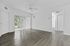 Bright, open living area with sleek hardwood flooring, ceiling fan, and sliding doors leading to lush greenery.