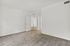 Bright and spacious room with plush carpet flooring, open doorway leading to a stylish corridor with wooden flooring, perfect for modern living.