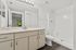 Modern and bright bathroom with elegant vanity, sleek fixtures, and a spacious shower, offering a serene escape.