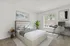 Bright and inviting bedroom showcasing a modern bed, sleek desk workstation, and large window with scenic outdoor view.