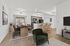 Modern open-concept dining and kitchen area with elegant furnishings, sleek hardwood floors, and inviting bar stools.