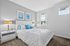 Bright and stylish bedroom with elegant white bed and chic decor, complemented by natural light and serene wall art.