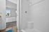 Bright and inviting bathroom with a modern shower, leading to a cozy bedroom with a large window view.